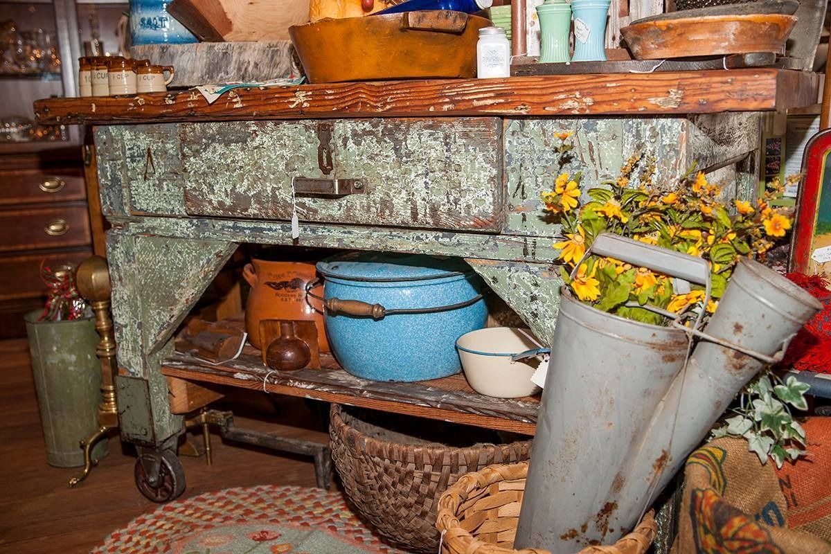 Rustic stone shelf with pots, baskets, flowers, and tools in a cluttered indoor room