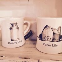 Two white mugs on a shelf labeled “Morning Love” and “Farm Life” with rustic illustrations