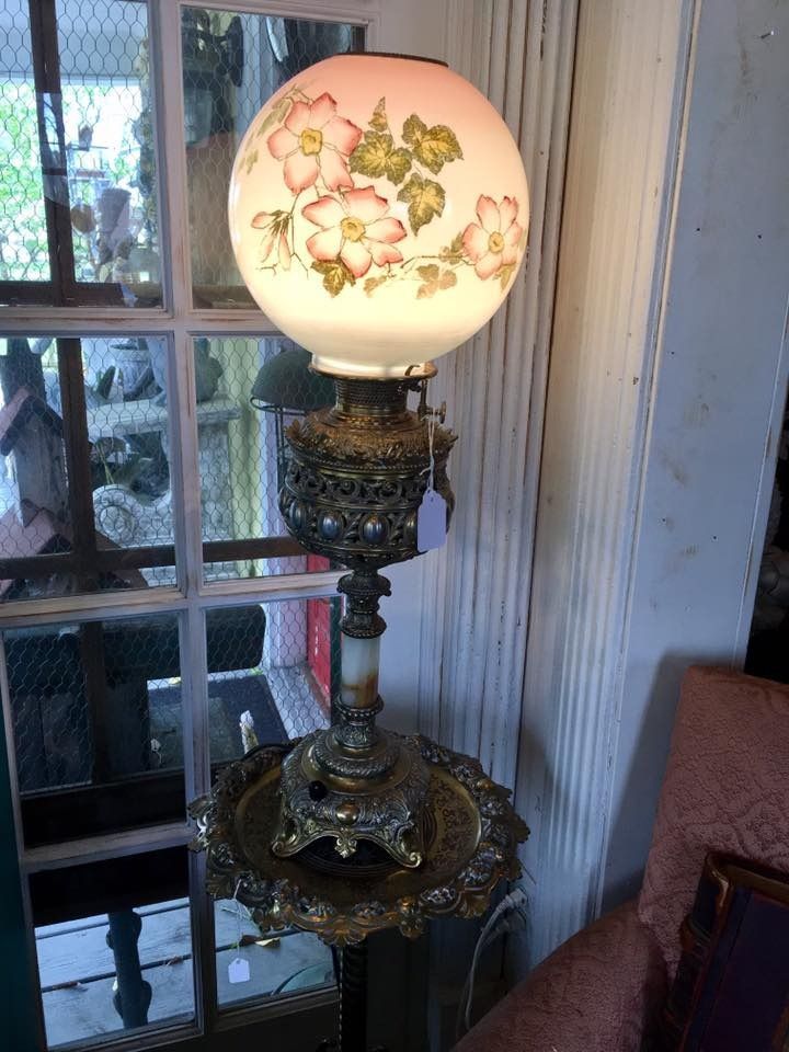 Vintage floral table lamp with frosted glass globe on an ornate metal stand near a window