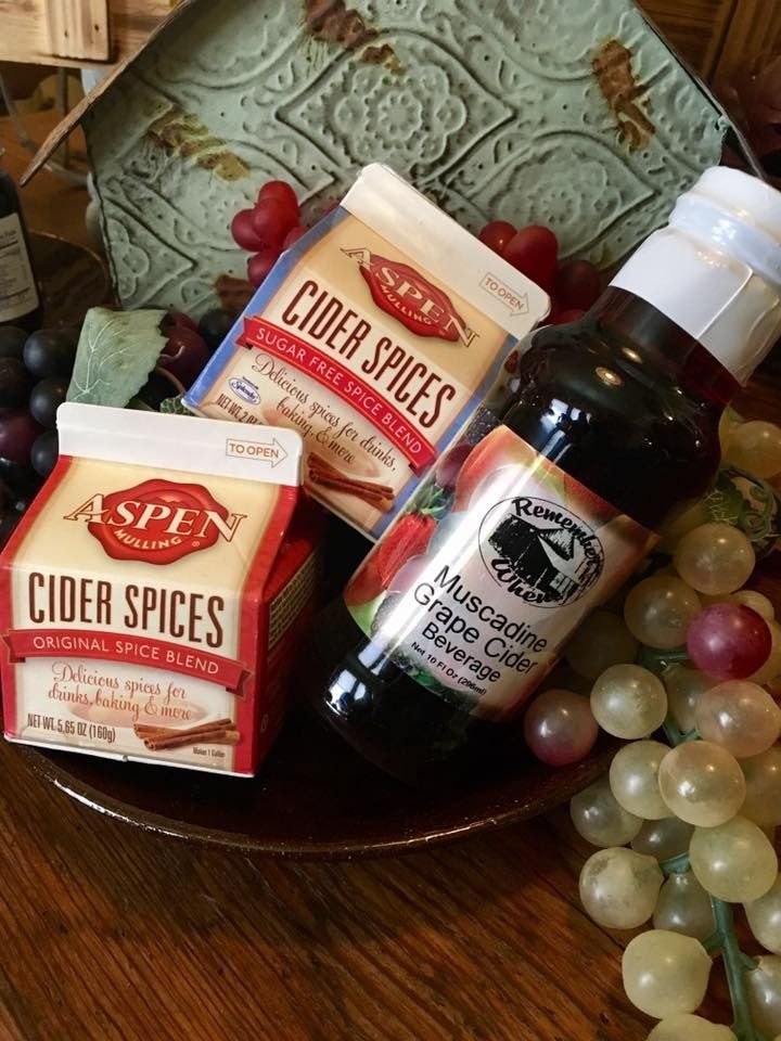 Cider spices boxes and a bottle of syrup on a decorative plate with grapes