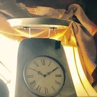 Close-up of a silver analog clock under bright yellow fabric or curtains