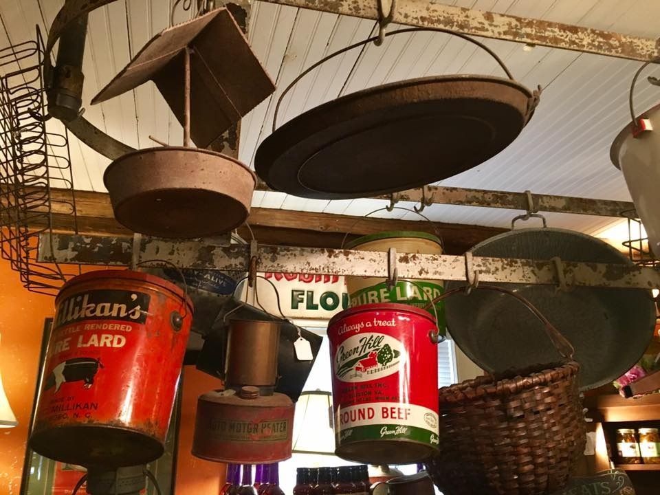 Rustic hanging cookware and vintage cans displayed under a canopy at a market stall.