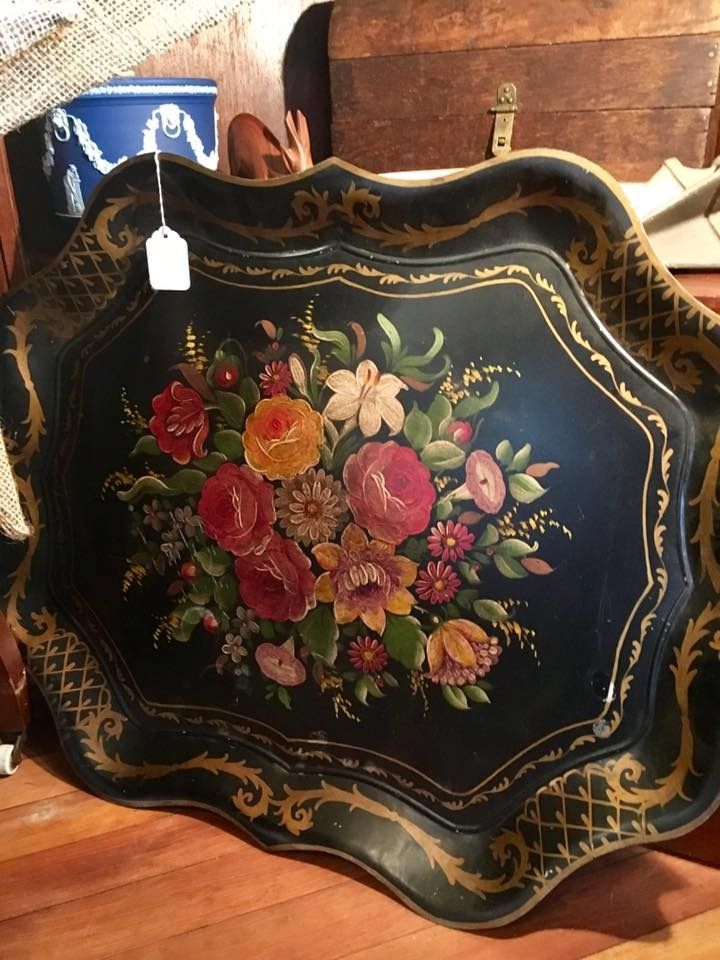 Black scalloped tray with gold trim and painted floral bouquet on a wooden surface