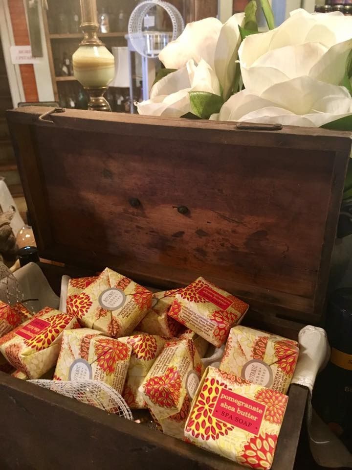Open wooden chest filled with wrapped gift boxes beside white flowers in a decorative display
