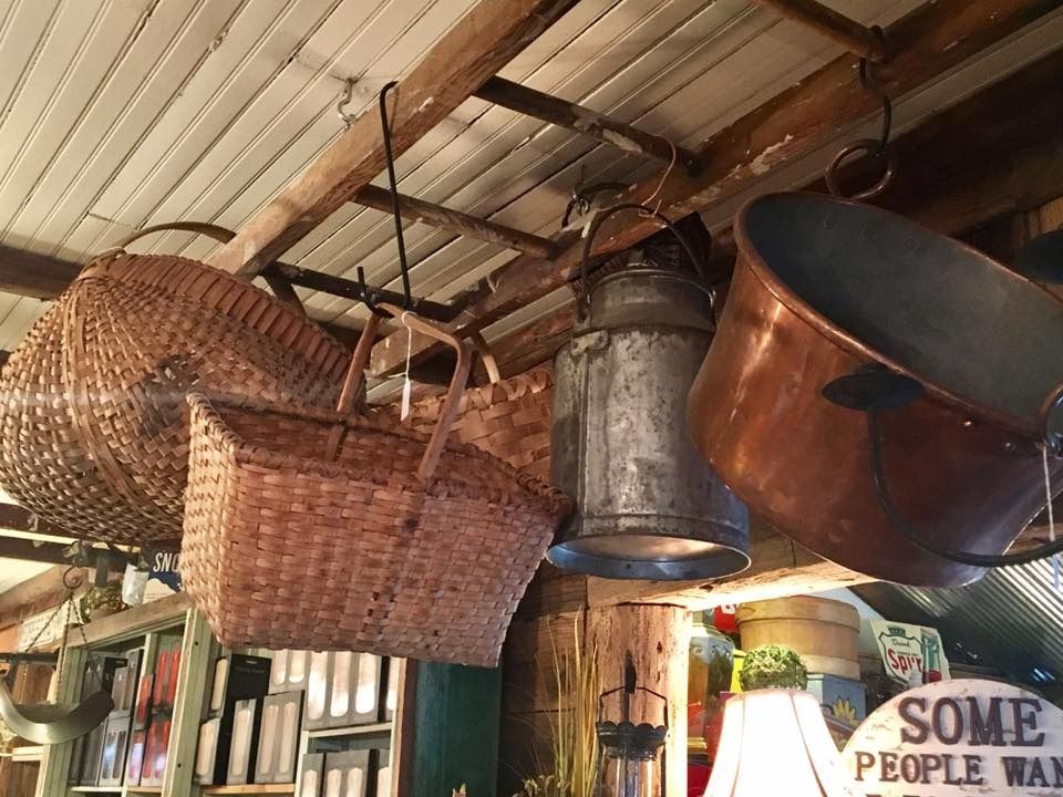 Woven baskets and hanging metal pots under a rustic ceiling in a cluttered shop interior