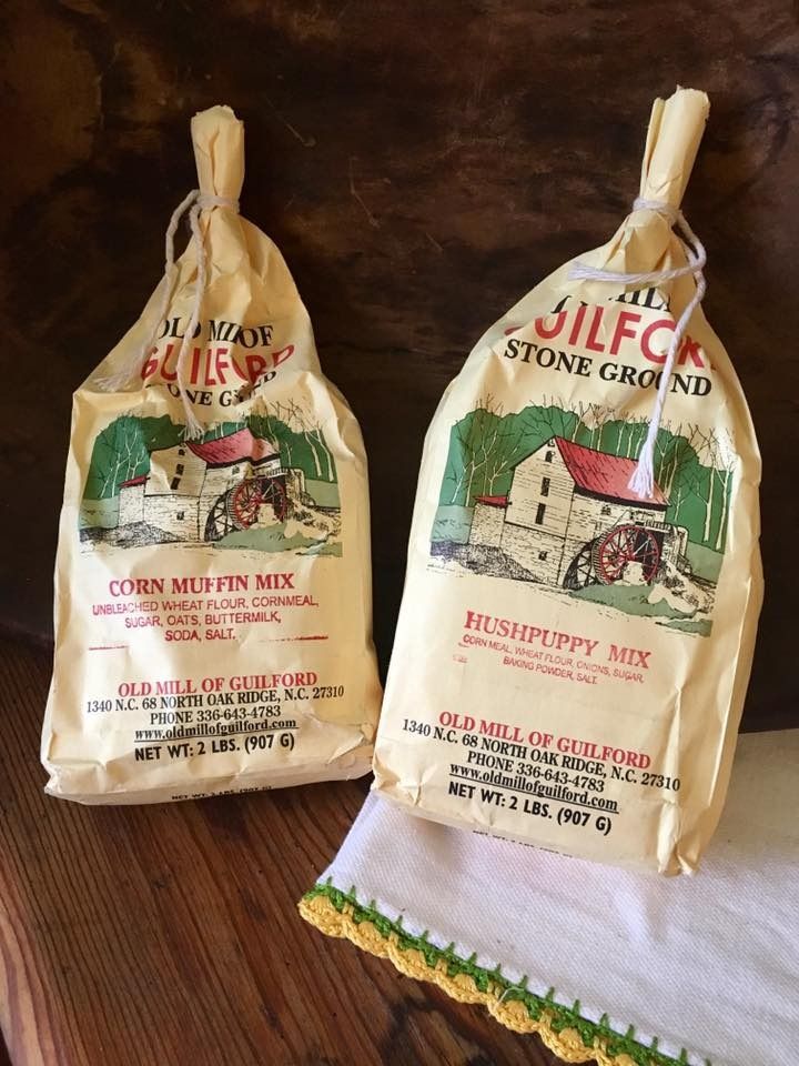 Two bags of Silco stone-ground cereal mix on a wooden table, one corn and one raspberry.