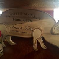 White wooden pig-shaped coat rack with “Farmers Market Pork Cut” text on a wooden table