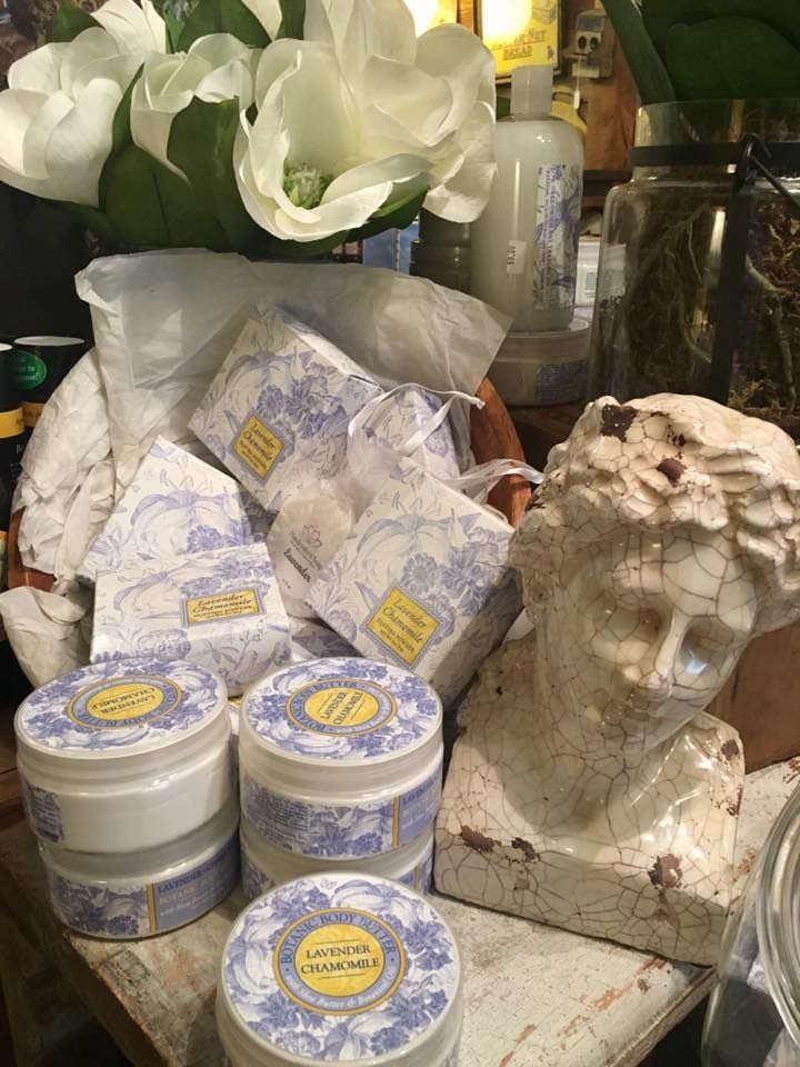 Display of lavender-scented bath products, floral decor, and a small white sculpture on a table