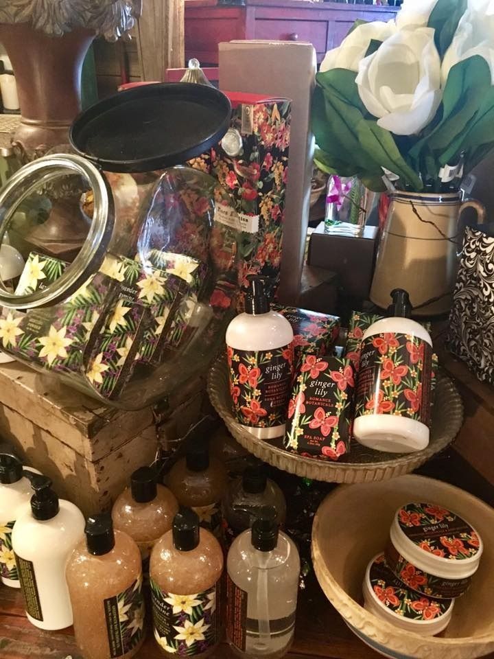 Assorted floral-patterned bottles, jars, and decor arranged on a table with a white flower centerpiece