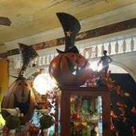 Halloween display with large pumpkin decorations, black witch hats, and autumn leaves in a shop interior