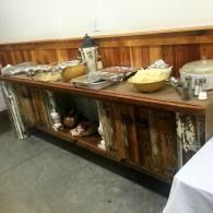 Buffet table with serving dishes and bowls on a rustic wooden sideboard in a dining room.