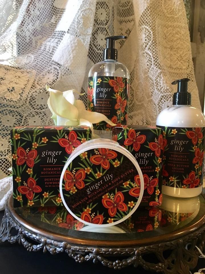 Floral gift set with lotion, soap, and candle on an ornate tray against lace curtains