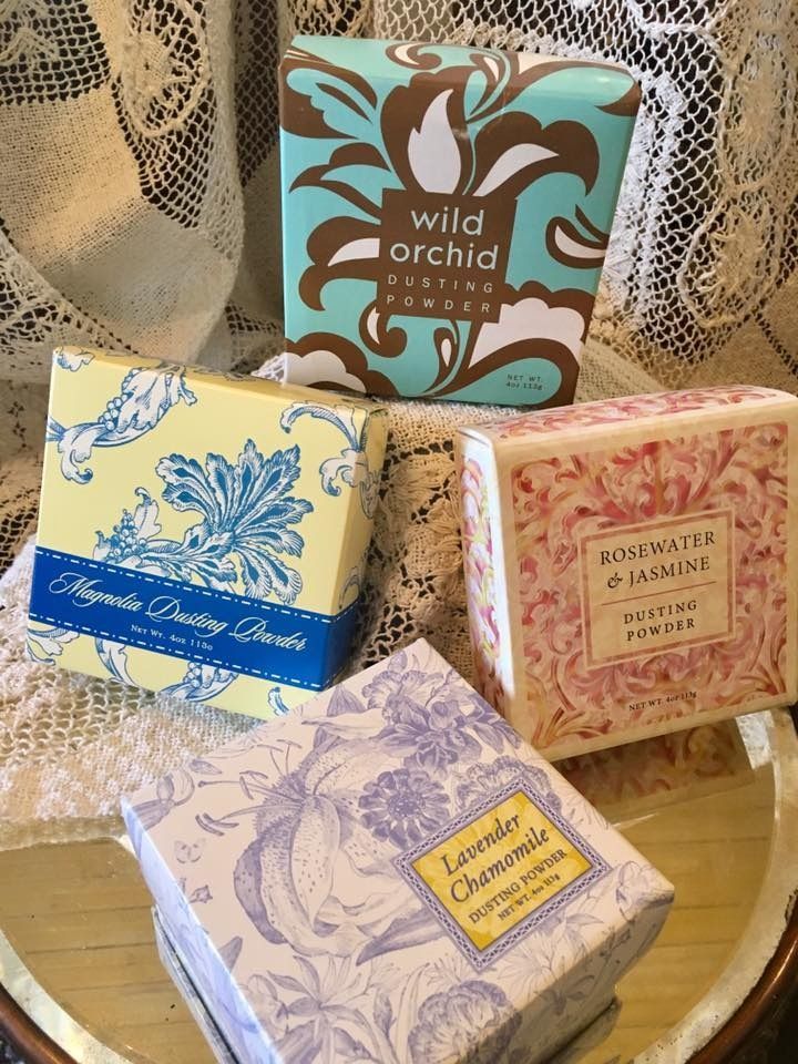 Assorted floral bath soap bars and boxes arranged on a tray against lace curtains