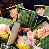 Assorted boxed flower bouquets in green-striped wrapping, piled together in a shop display