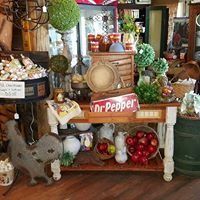 Rustic produce display with Dr Pepper sign, fruits, baskets, and potted greenery in a cozy shop interior