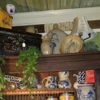 Decorative shelf with ceramic vases, mugs, and a trailing plant under a wooden ledge