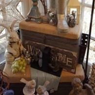 Rustic fall display with a vintage stove, pumpkins, gourds, and small decorative figurines indoors