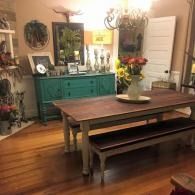 Cozy dining room with teal sideboard, wooden table, flowers, and warm lighting