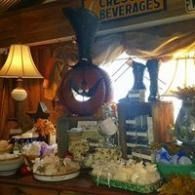 Decorated buffet table with pastries, flowers, lamp, and beverage sign in a cozy room