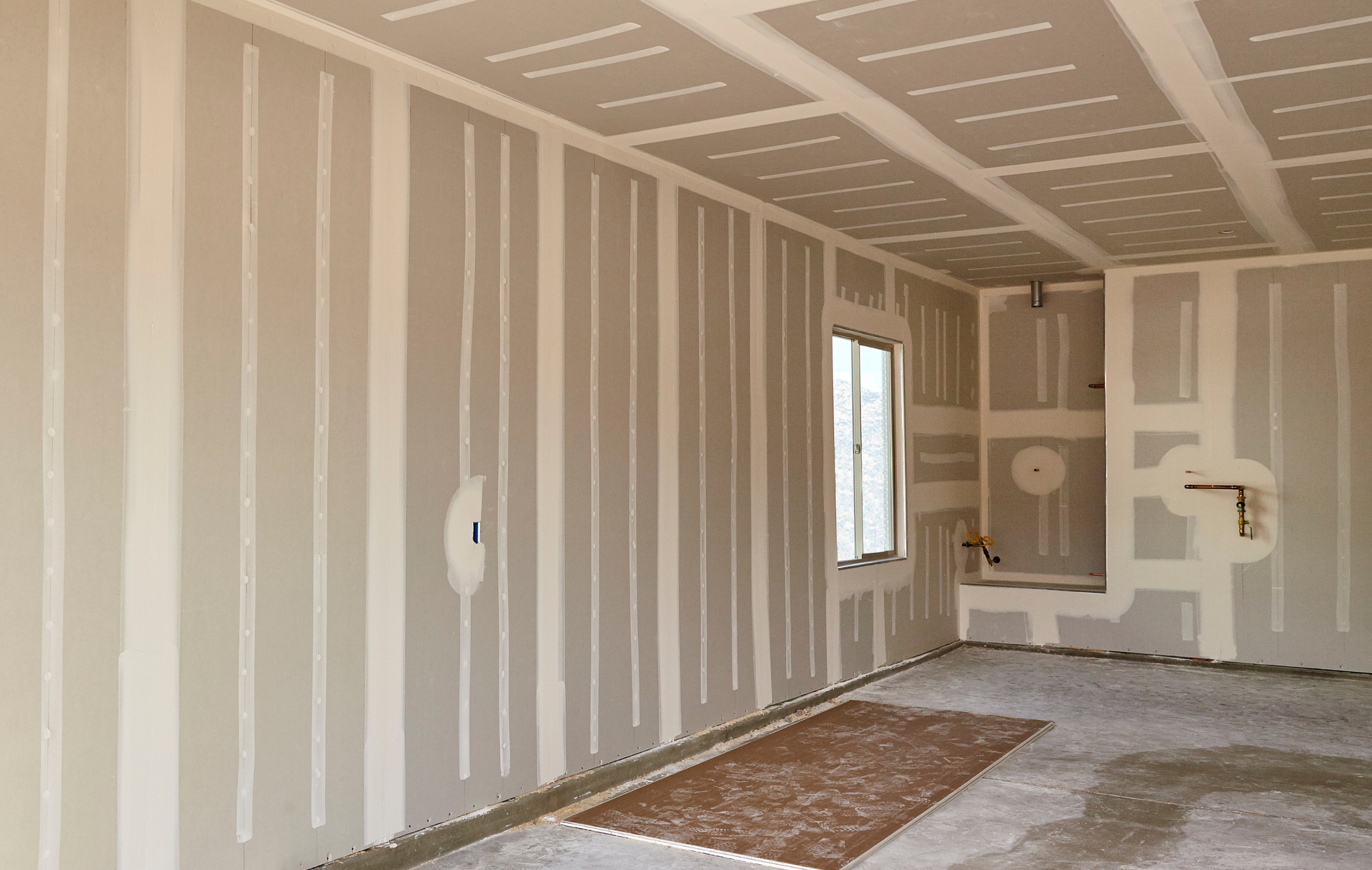 An empty room with drywall on the walls and ceiling.