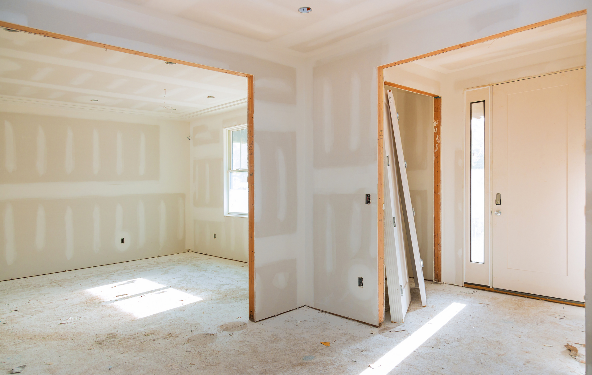 An empty room in a house under construction with drywall on the walls.