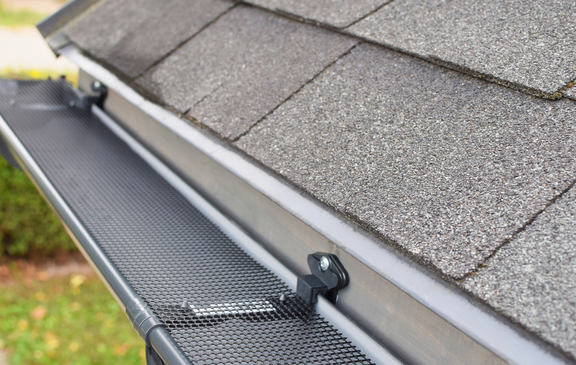A close up of a gutter on a roof with shingles.
