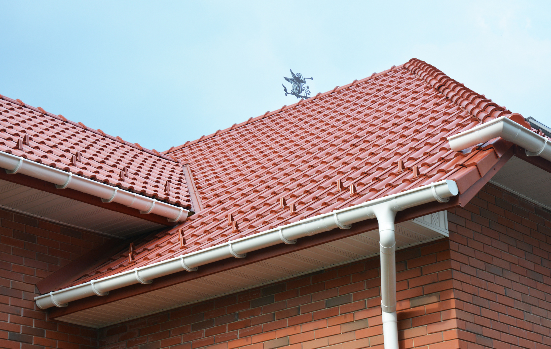 A brick building with a red tiled roof and a white gutter.