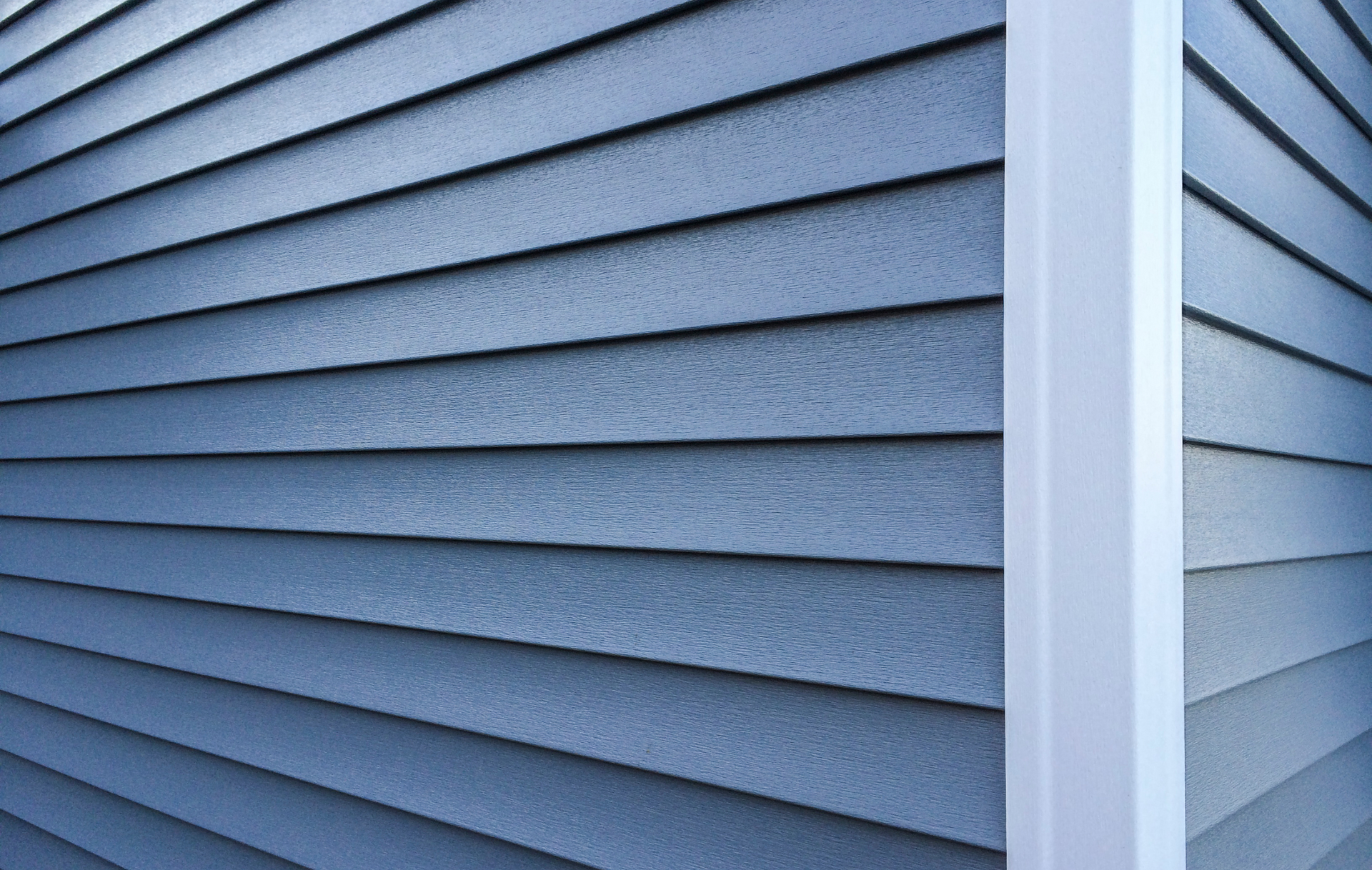 A close up of a blue siding on a house with a white trim