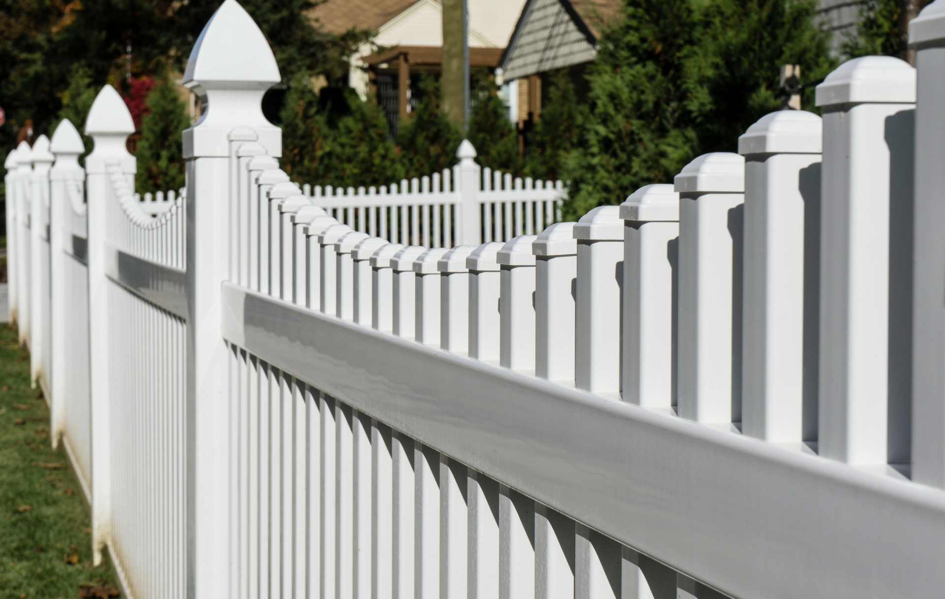 A white picket fence with a house in the background