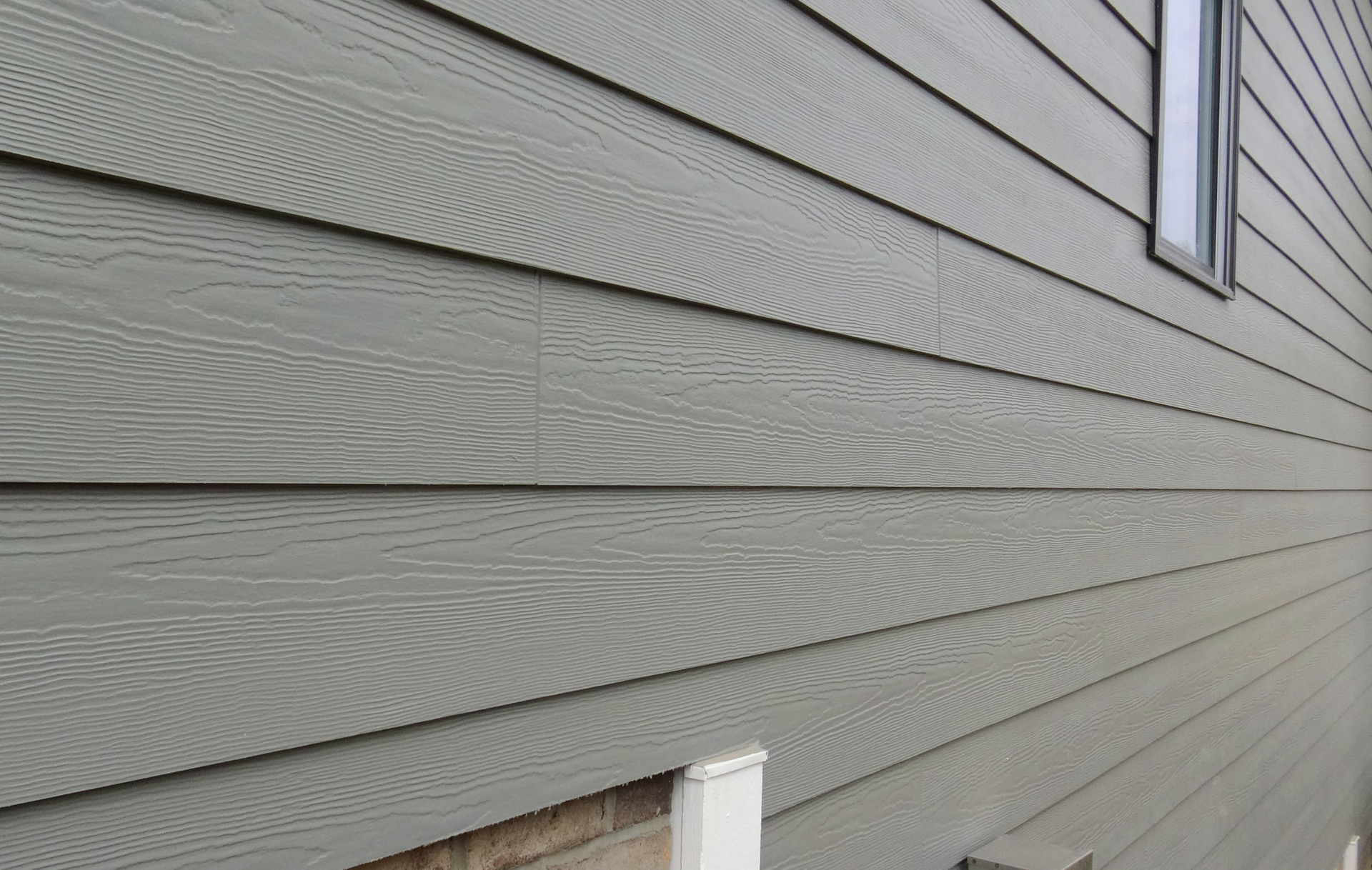 A close up of a house with a gray siding and a window.