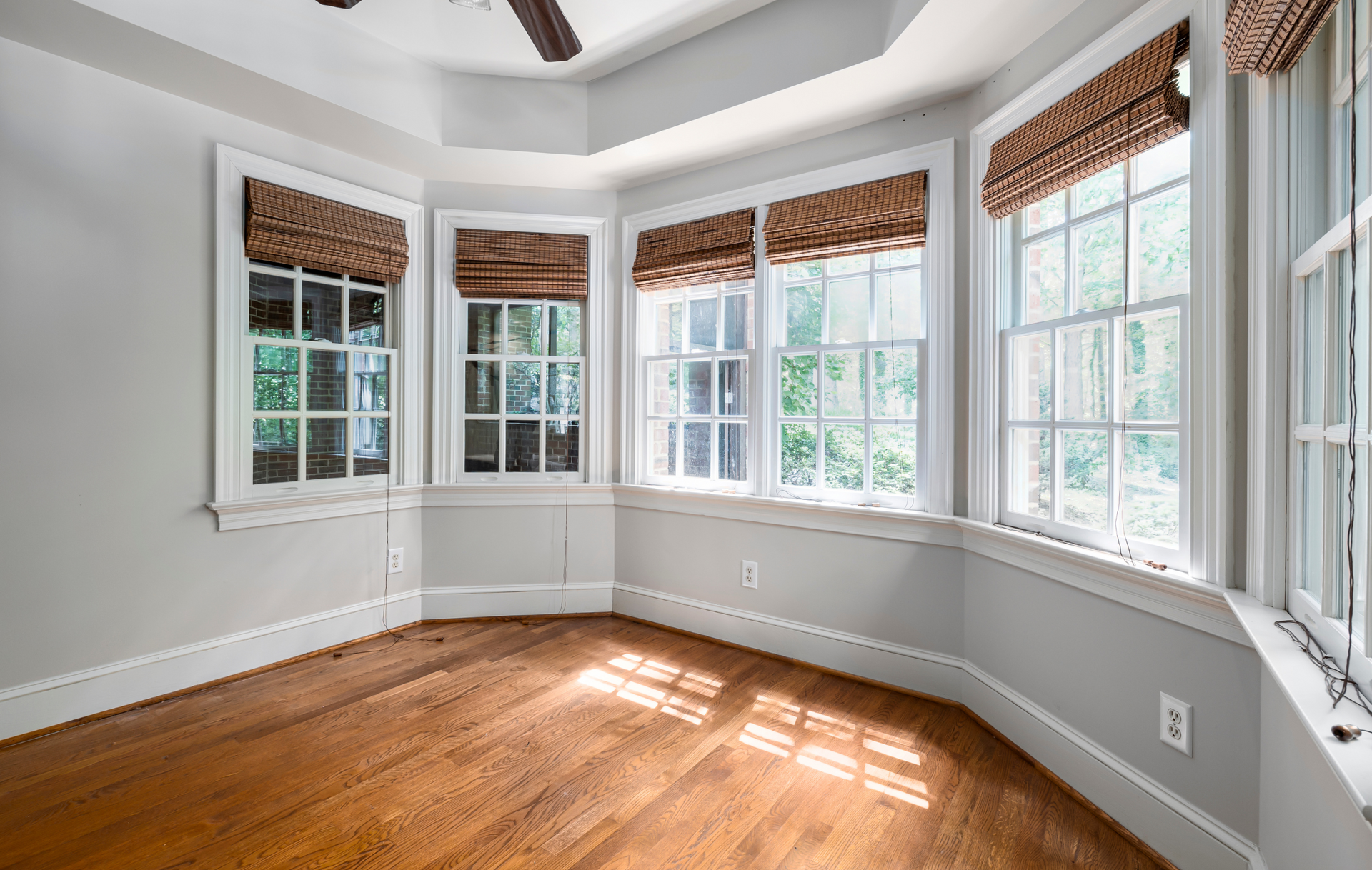 An empty room with hardwood floors and lots of windows.