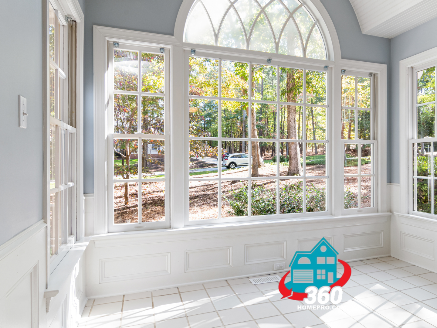 An empty room with a lot of windows and trees in the background.