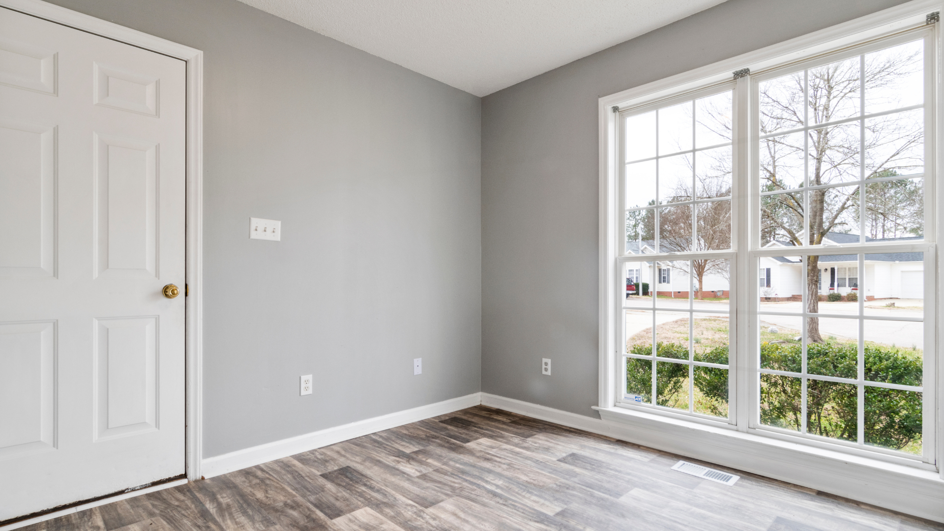 An empty room with a large window and a door.