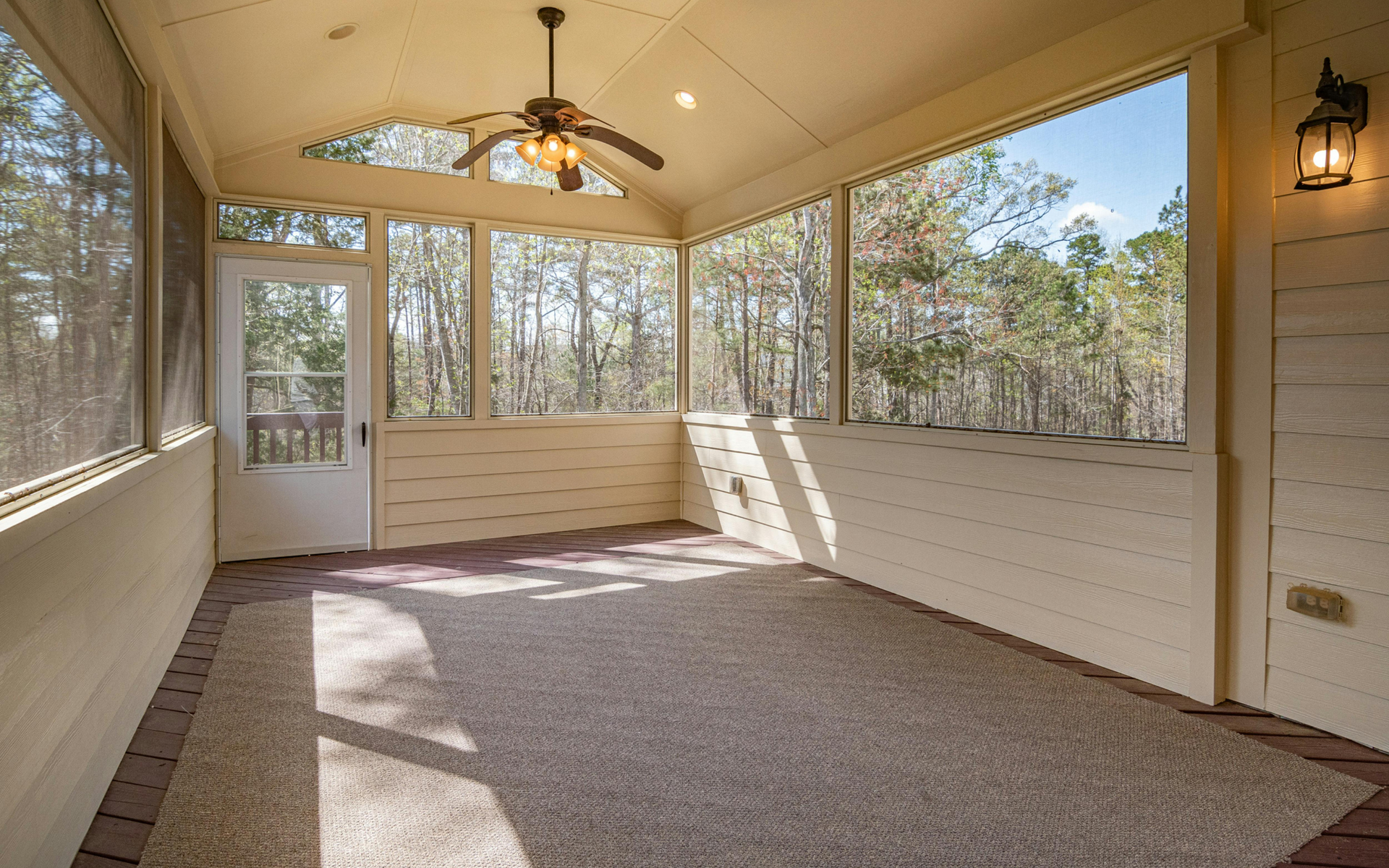 A screened in porch with a ceiling fan and a lot of windows.