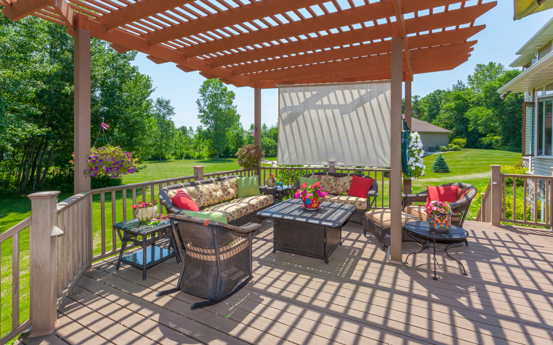 There is a pergola over the deck with a lot of furniture on it.