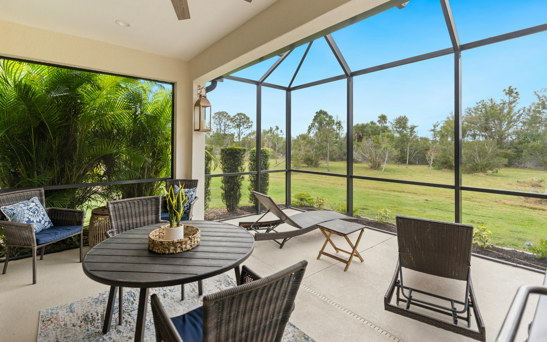 A screened in porch with a table and chairs and a view of a field.