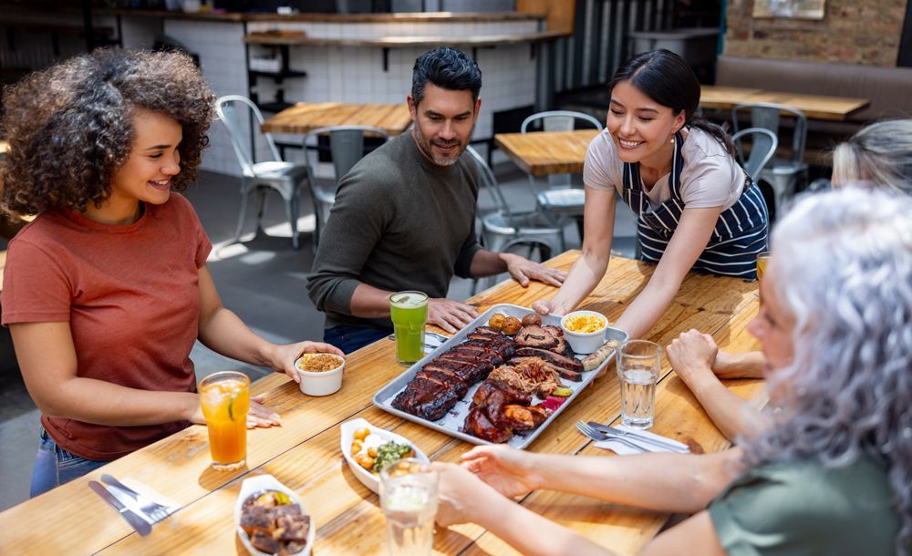 people being served bbq while sitting at a dining table in a restaurant