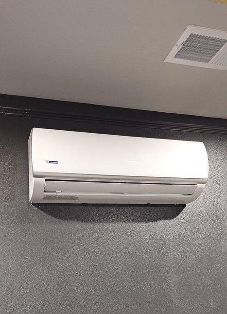 White air conditioning unit mounted on a gray textured wall.