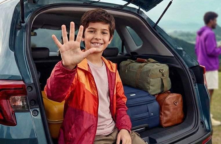 Menino sentadono porta malas do Honda WR-V 2026, fazendo sinal de 5 com a mão