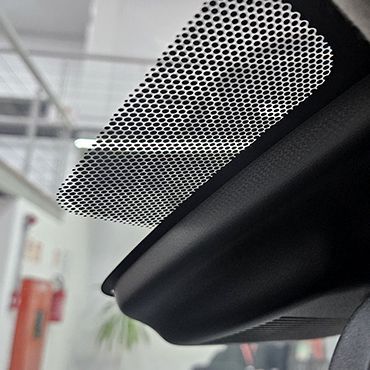 Área pontilhada preta no para-brisa do carro, provavelmente para sensores, perto do espelho retrovisor. Ambiente interno.