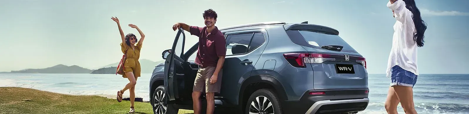 Pessoas ao redor do Honda WR-V na praia, com clima descontraído, dança ao lado do SUV azul