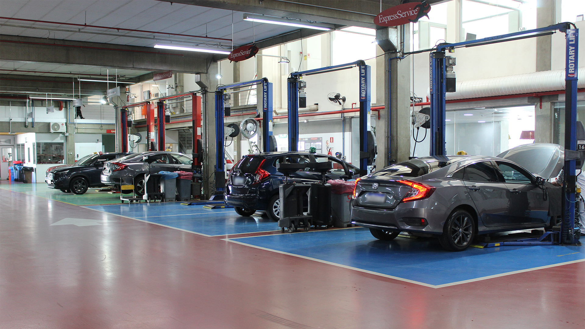 Carros em uma oficina mecânica bem iluminada, em elevadores, com ferramentas e equipamentos