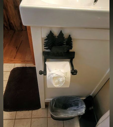 A toilet paper holder in a bathroom with trees on it