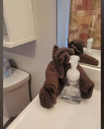 A towel is sitting on a bathroom sink next to a spray bottle.