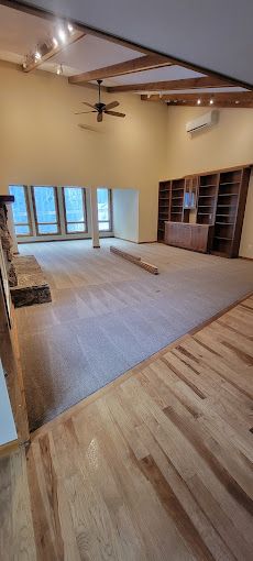 A large empty room with hardwood floors and a ceiling fan.