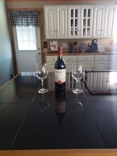 A bottle of wine and two wine glasses are on a kitchen counter.
