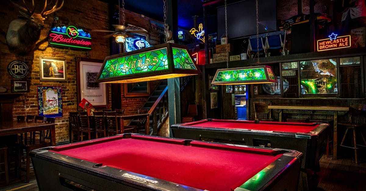 There are two pool tables in the middle of a bar.