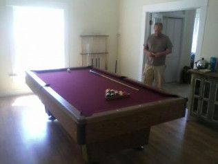 A man standing next to a pool table in a room