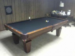 A pool table is sitting in a room next to a desk.