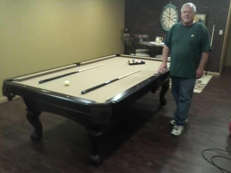 A man in a green shirt stands in front of a pool table